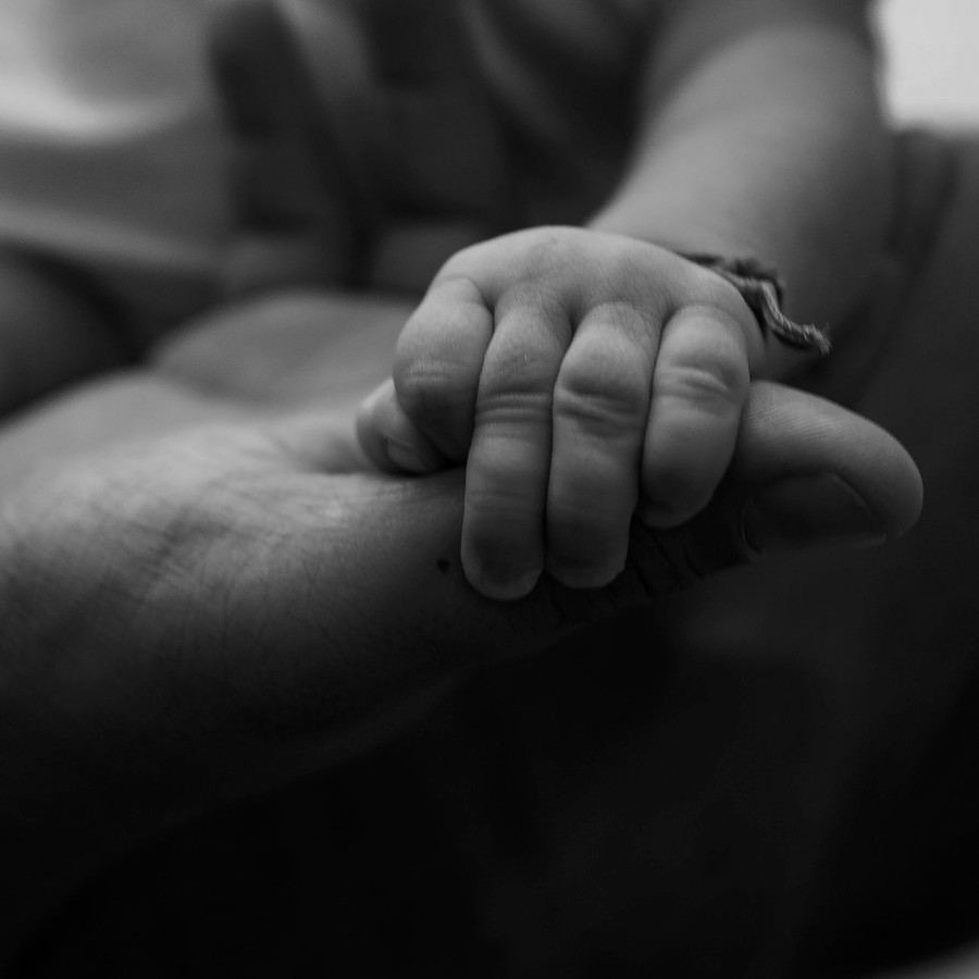 어른의 손과 아기의 작은 손이 맞닿아 있는 흑백 사진, 배우자의 출산·육아 참여를 상징